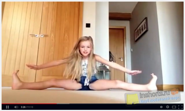 Маленькая девочка в шортах дает уроки гимнастики дома